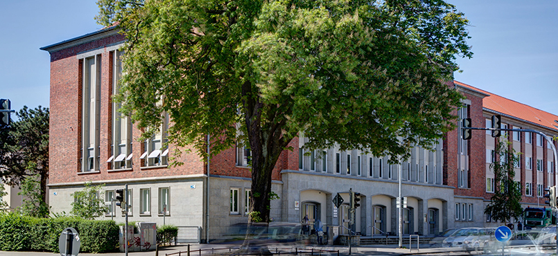 Das Gebäude Haus der Justiz im Sommer von einem Baum verdeckt