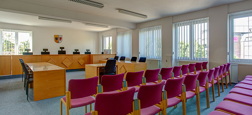 Verhandlungssaal mit roten Stuhlreihen, Blick auf das Richterpodium